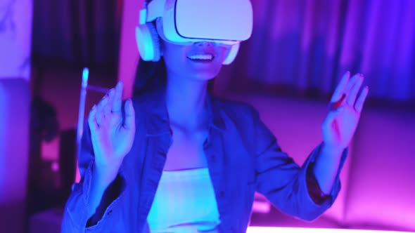 Young asian woman is using virtual reality headset. Neon light studio portrai