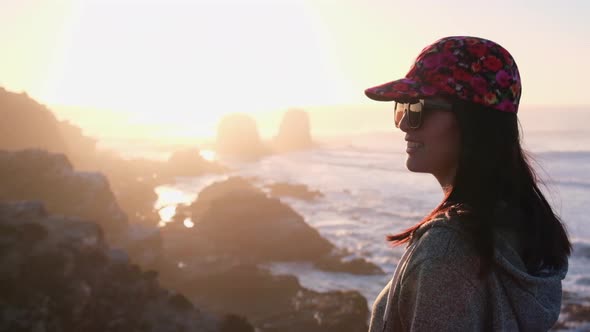 woman from back watching the sunset with the sun in the sea on surf beach in punta de lobos