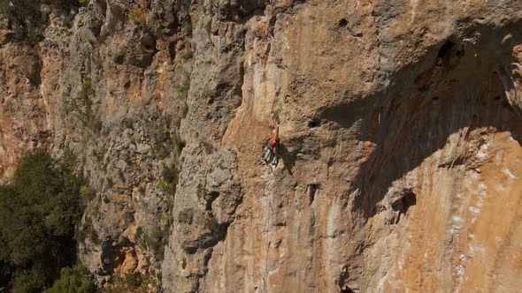 Aerial View From Drone of Strong Muscular Young Man Hanging on Rope and Descenting After Climbing on