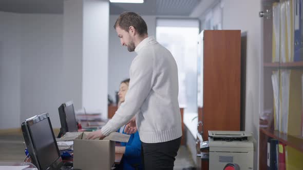 Brunette Bearded Caucasian Man Packing Belongings in Office in Cardboard Box