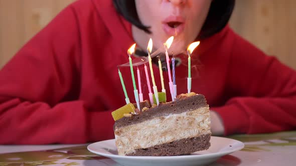 Happy Girl Blows Out Candles on a Birthday Piece of Cake