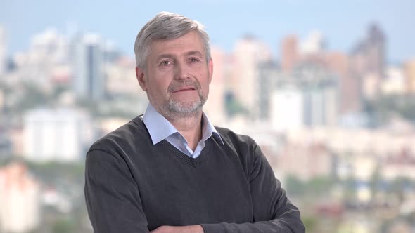 Mature Man with Arms Crossed on Blurred Background