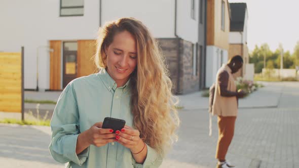 Positive Woman Booking Taxi on Smartphone on Street