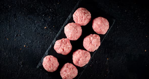 Raw Meatballs on a Stone Board Rotate Slowly. 