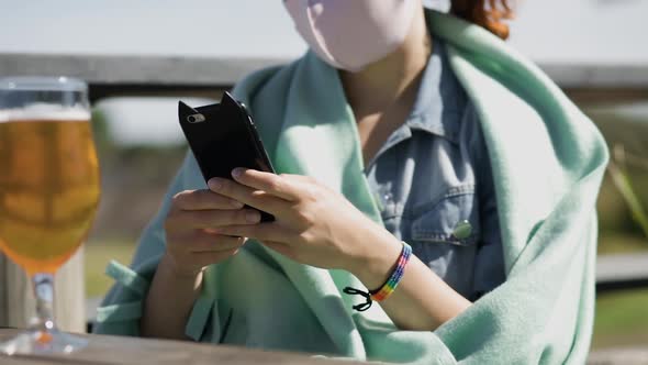 Young Lesbian Woman Texts Her Girlfriend Via Smartphone in Cafe Wearing Rainbow Bracelet and Face