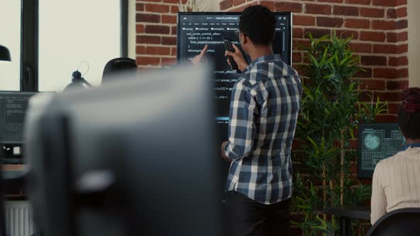 Team of Coders Analyzing Code on Wall Screen Tv Comparing Errors Using Digital Tablet