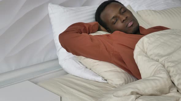 AfroAmerican Man Tosses and Turns Sleeping in Bed at Home