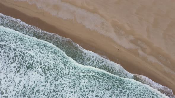 Aerial view of waves crash to beach