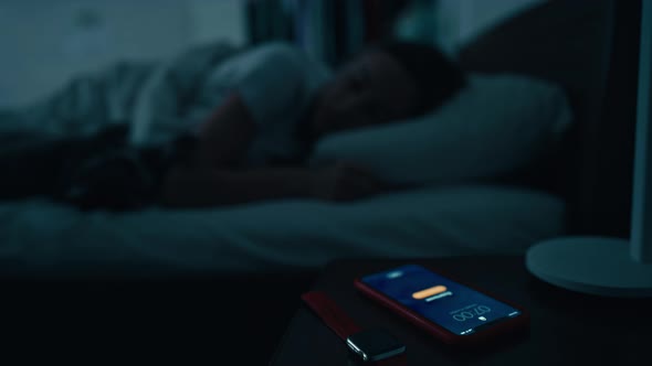 Young Sleeping Woman Wakes Up Early in Morning to Disable Activated Smartphone Alarm on Bedside