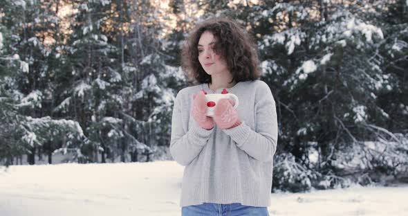 Cute Curly Girl Drinks Warm Tea In The Winter Snowy Forest