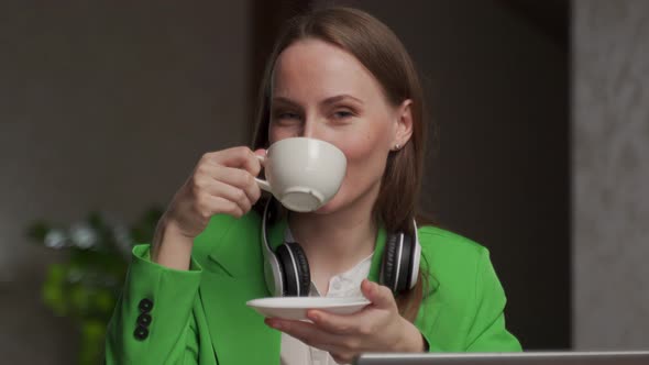 Woman Enjoys Aromatic Coffee in White Cup Looking in Camera