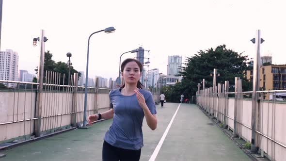 Athlete young Asian woman running on the street in the city workout lifestyle at sunset.