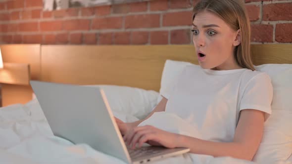 Upset Young Female Reacting to Loss on Laptop in Bed