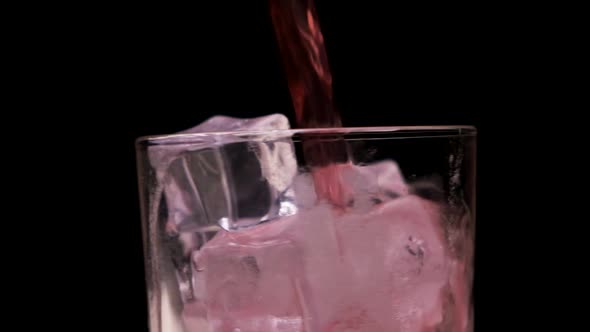 A Red Liquid is Poured Into a Clear Glass Glass with Ice