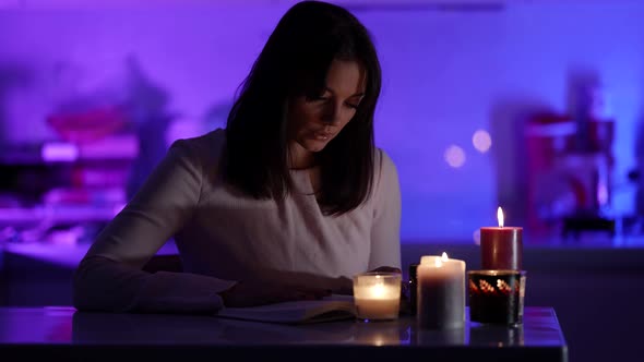 Romantic Lady Is Reading Book By Candlelight at Night in Dark Room