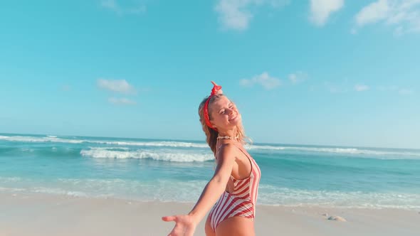 Young Caucasian Woman in Swimsuit Spinning Around Herself Stands on Sea Beach