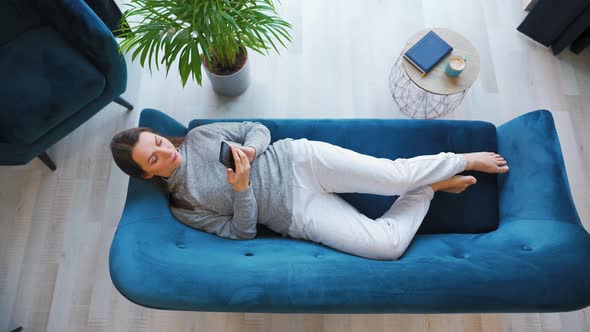 Overhead Shot of Happy Relaxed Woman Holding Smart Phone Using Mobile Apps Watching Funny Video