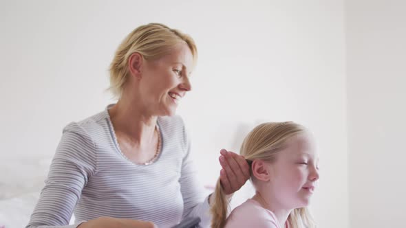 Side view of Caucasian woman brushing hair of her daughter