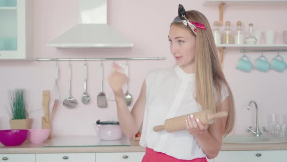 Dissatisfied Young Woman Holding Rolling Pin and Calling Someone. Portrait of Irritated Angry