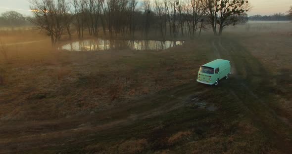 Vintage bus rides in the fog, among the trees at dawn. 