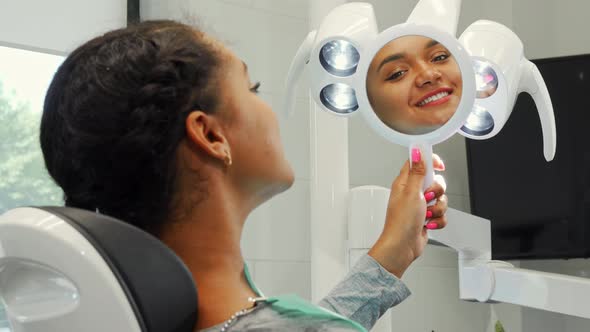 Cheerful African Woman Smiling Examining Her Healthy Smile in the Mirror