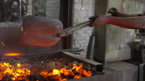 Man Mixing Coals in Stove with Shovel