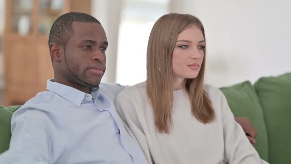 Mixed Race Couple Sitting on Sofa and Smiling at Camera