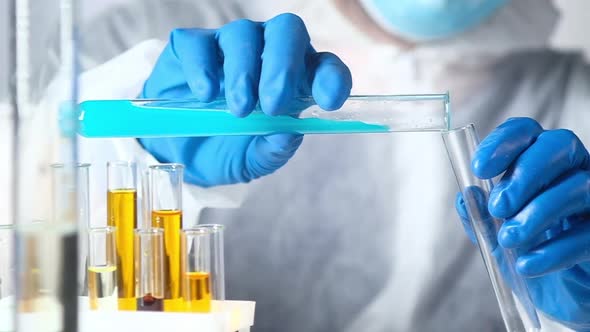 scientist working with chemical reagents and solutions pours liquid in test tube
