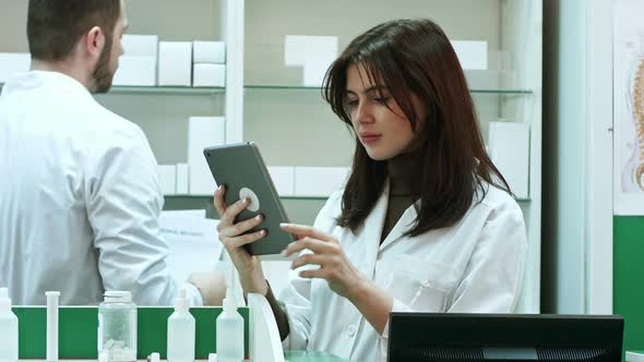 Female Pharmacist with Digital Tablet Searching for Medication