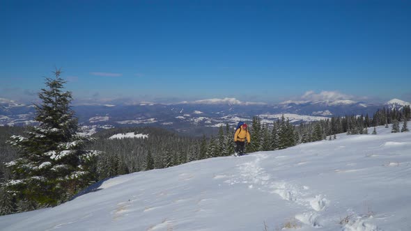 A Man with a Backpack Travels in the Mountains in Winter