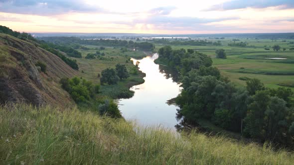 Panoramic View of River Between Fields During Sundown.