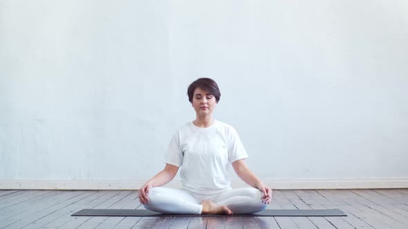 Young and fit woman practicing yoga indoor in the class.