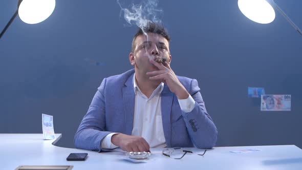 Businessman smoking cigar in his office. Rich businessman.