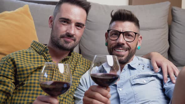 Gay Couple in Love Sitting at Home on the Floor and Toasting with Red Wine