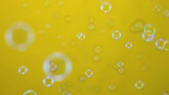 Beautiful Colored Soap Bubbles Fly Indoors on a Yellow Background