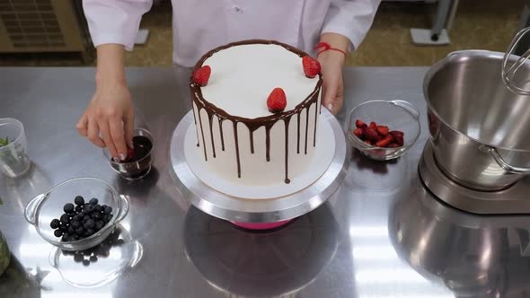 The Pastry Chef Decorates the Cake with Chocolatecovered Strawberries