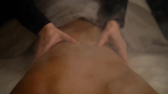 Close Up Spa Hotel Massage Woman Back. Therapist Hands Do Massage To a Woman in a Dark Room with