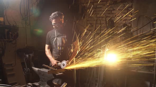 Man Working the Angle Grinder in Workshop. Blacksmith Working with Metal