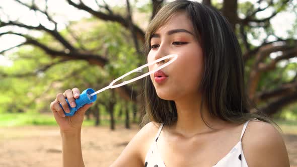 Young South East Asian 20s Woman Blowing Air Bubbles in Park
