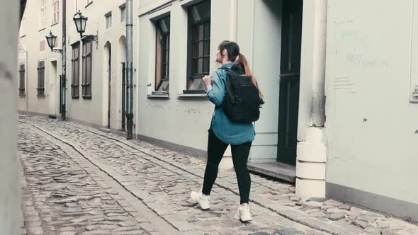 a woman tourist with a backpack walks along the street of the ancient city.