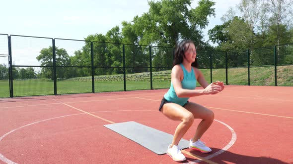 Fitness Woman in Sportswear Doing Various Exercises on Sports Mat, on an Orange Basketball Field