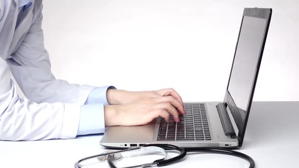 Doctor Typing Important Information on the Computer, White