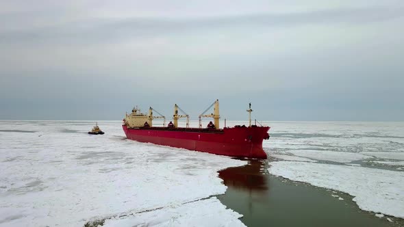 Aerial Above Epic Huge Steel Icebreaker Breaks Ice By Bow of Ship and Floats in Large Sea Ice Floes