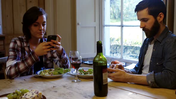 Couple using mobile phone while having meal