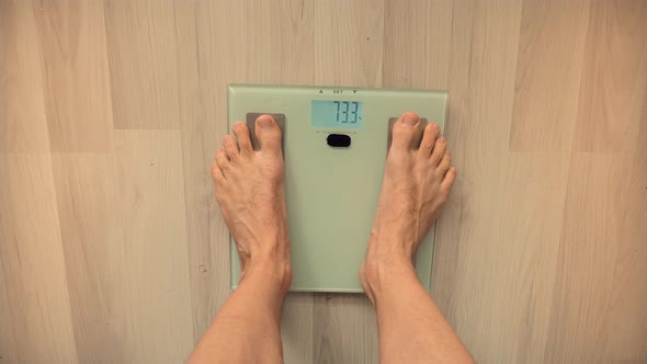 Man On Scales Measure Weight.Guy Legs Step On Bathroom Scale.Diet Man Feet Standing Weighing Scales