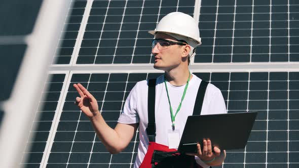 Technician with a Laptop Is Observing Solar Panels. Alternative Energy Worker Near Solar Energy