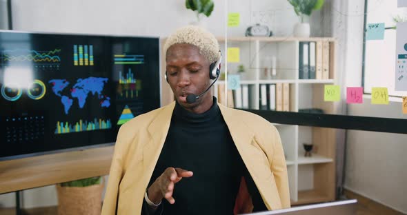 African American Male Office Worker with Headphones Talking Into Camera