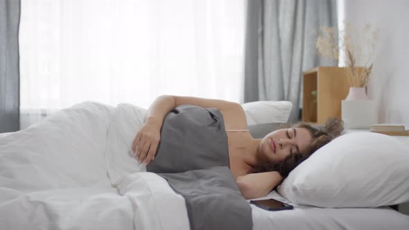 Pretty Woman Waking Up in Bed and Using Smartphone