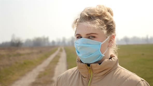 A Girl in a Medical Mask Turns to the Camera