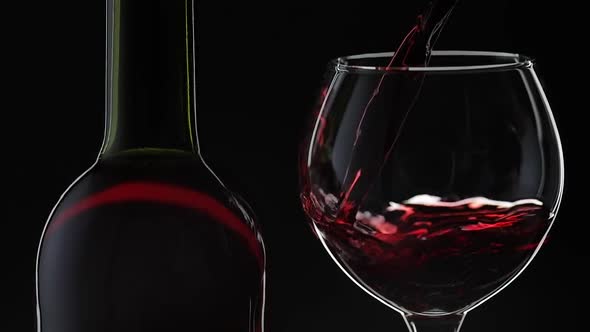 Rose Wine. Red Wine Pour in Wine Glass Over Black Background. Slow Motion